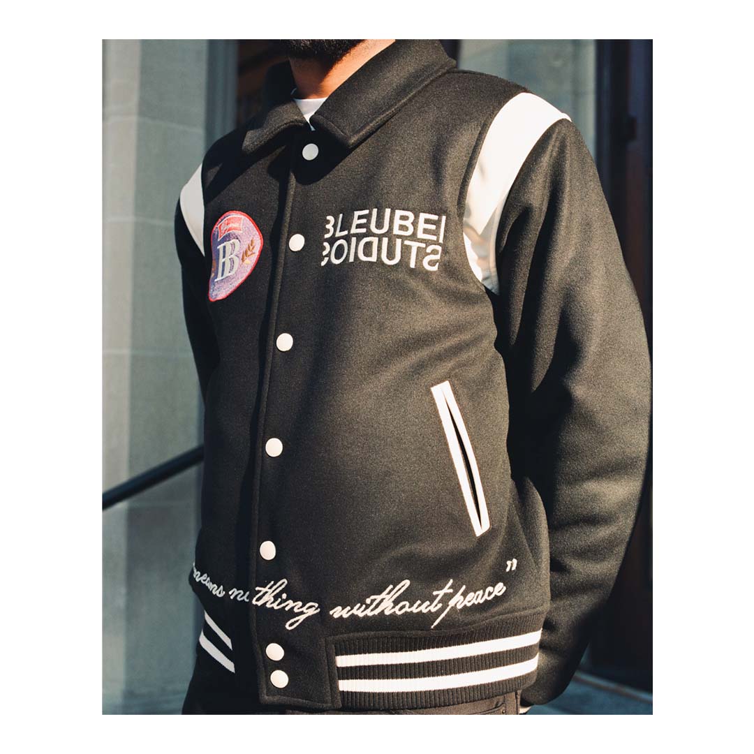 Black Melton body and sleeves/neck fabric Cream Leather shoulder and pocket Cream buttons Black and cream stripe rib design for the cuffs and hem Embroidered logo patch on front left chest Embroidered logo on right left chest Chainstitch embroidery quote on waistline Embroidery doves logo on back varsity jacket