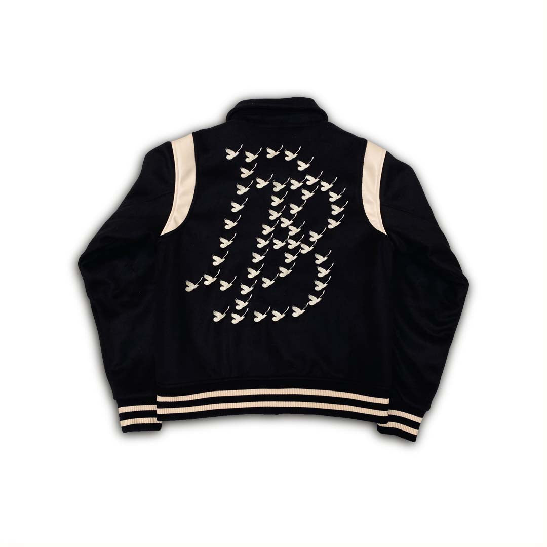 Black Melton body and sleeves/neck fabric Cream Leather shoulder and pocket Cream buttons Black and cream stripe rib design for the cuffs and hem Embroidered logo patch on front left chest Embroidered logo on right left chest Chainstitch embroidery quote on waistline Embroidery doves logo on back varsity jacket